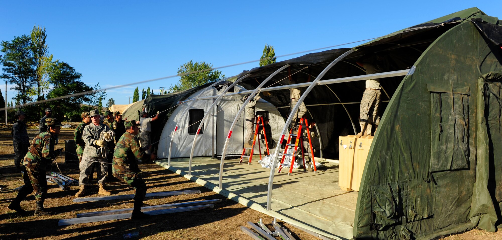 Airmen from an Air Force Expeditionary Medical Support team along with members of the Chilean army pull the roof over a mobile hospital March 12, in Angol, Chile. The EMEDS team is adding an additional operating room and three patient wards to the facility at the request of local Chilean medical officials. (U.S. Air Force photo/Senior Airman Tiffany Trojca)

