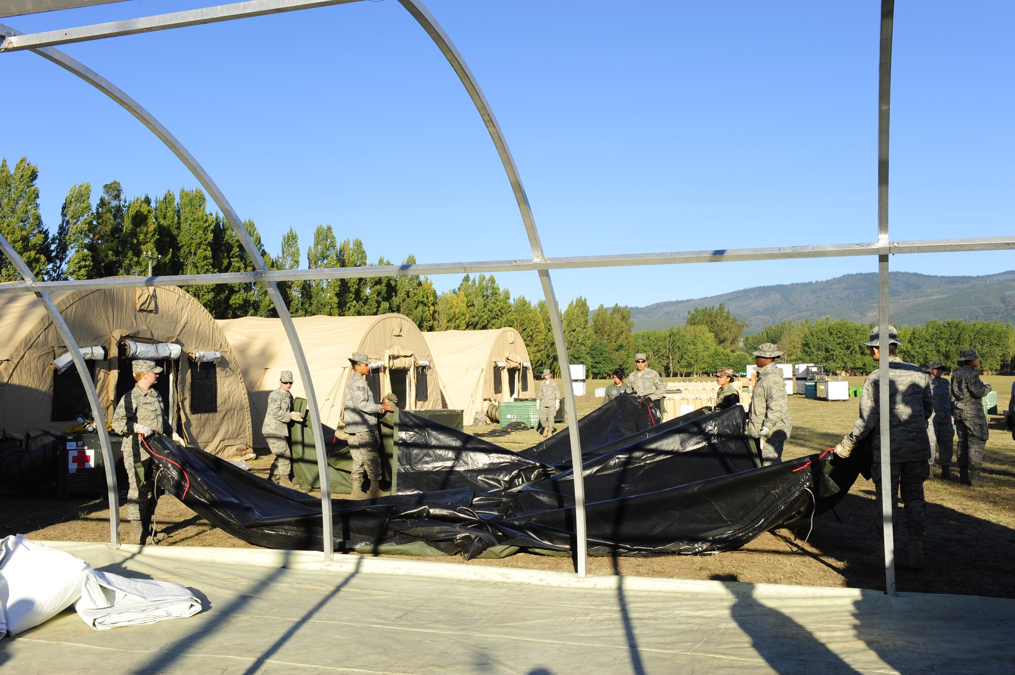 Airmen from an Air Force Expeditionary Medical Support team along with members of the Chilean army prepare a tarp that will be used as a roof for a mobile hospital March 12, in Angol, Chile. The EMEDS team is adding an additional operating room and three patient wards to the facility at the request of local Chilean medical officials. (U.S. Air Force photo/Senior Airman Tiffany Trojca)
