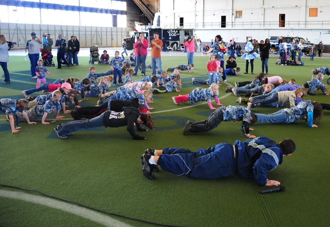 ELLSWORTH AIR FORCE BASE, S.D. -- Children of Ellsworth's Airmen line up and do push-ups for a physical training demonstration during Kids, Spouses and Teachers Understanding Deployment Operations event, March 13.  Senior Airman Zachary Christy, 28th Force Support Squadron food services specialist, teaches the children how to work together and do a proper push-up. (U.S. Air Force photo/Airman 1st Class Anthony Sanchelli)
