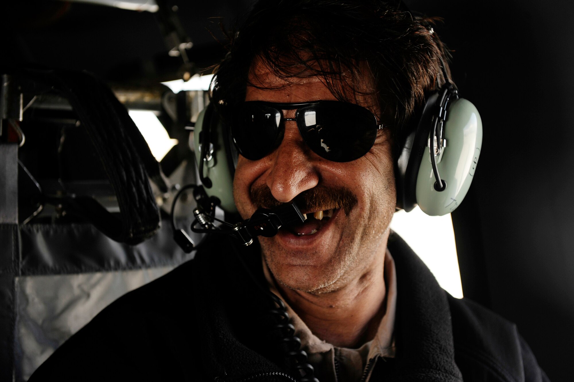 Sergeant Abdul Wali, an Afghan National Army Air Corps crew chief, similes at his peers during a flight on a UH-60 Blackhawk, March 01, 2010, over Parwan Province, Afghanistan. Sergeant Wali is a student in the U.S.-run air crew acadamy.  The air crew academy is one of two academies within the Task Force Falcon Combined Action Program, the other being an Afghan National Security Forces air-assault academy. The joint team hopes to have 25 Afghan crew chiefs trained before the end of the year.  (U.S. Air Force photo/Staff Sgt. Manuel J. Martinez/released)
