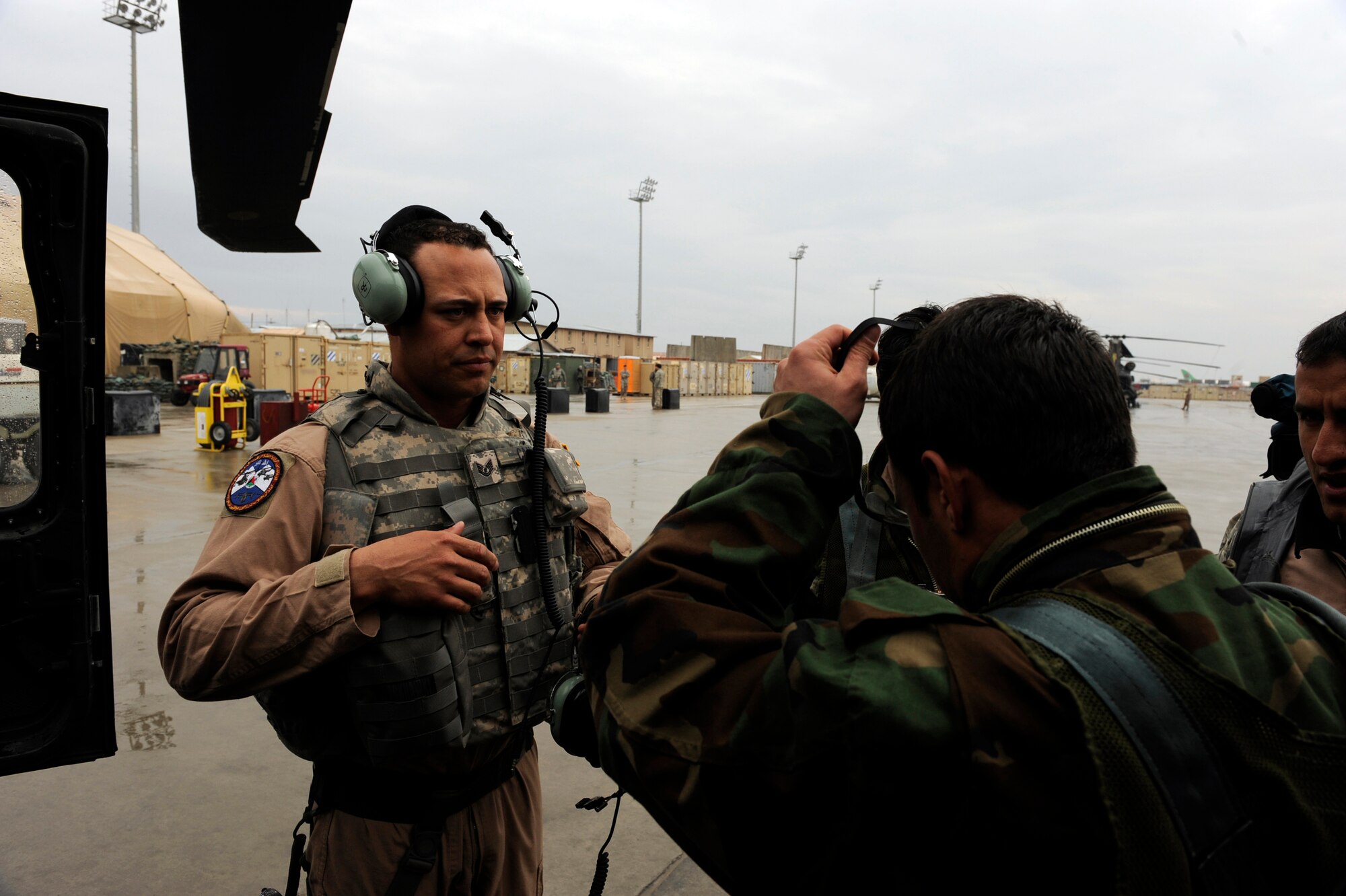 Tech. Sgt. Garrett Cain, a rotary-wing crew chief mentor assigned to 440th Air Expeditionary Advisor Squadron, helps gear-up one of his Afghan National Army Air Corps crew chief students before boarding a UH-60 Blackhawk helicopter, Feb. 28, 2010, at Bagram Airfield, Afghanistan. ?This has been an amazing experience and I am extremely proud of our students,? said Sergeant Cain, who is deployed from Nellis Air Force Base, Nev. ?These ANAAC soldiers made great strides during the course and their accomplishment brings them one step closer to helping them aid in their nation's security.?  (U.S. Air Force photo/Staff Sgt. Manuel J. Martinez/released)
