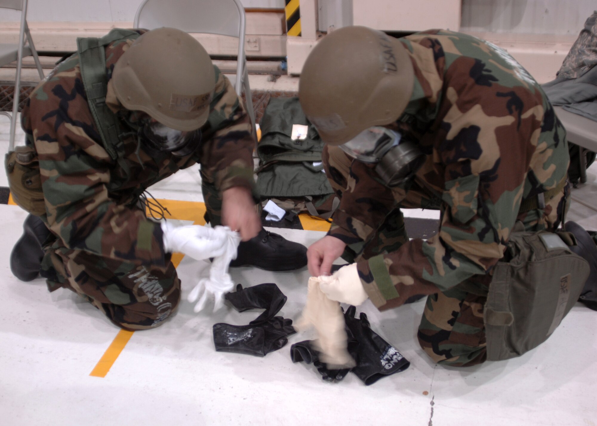 GRISSOM AIR RESERVE BASE, Ind. -- Senior Airman Kenneth Moore, 434th Aircraft Maintenance Squadron crew chief, and Airman 1st Class Patrick Harris, 434th AMXS crew chief, work quickly to put-on their protective gloves, during an ability to survive and operate exercise.  (U.S. Air Force photo/Senior Airman Carl Berry)