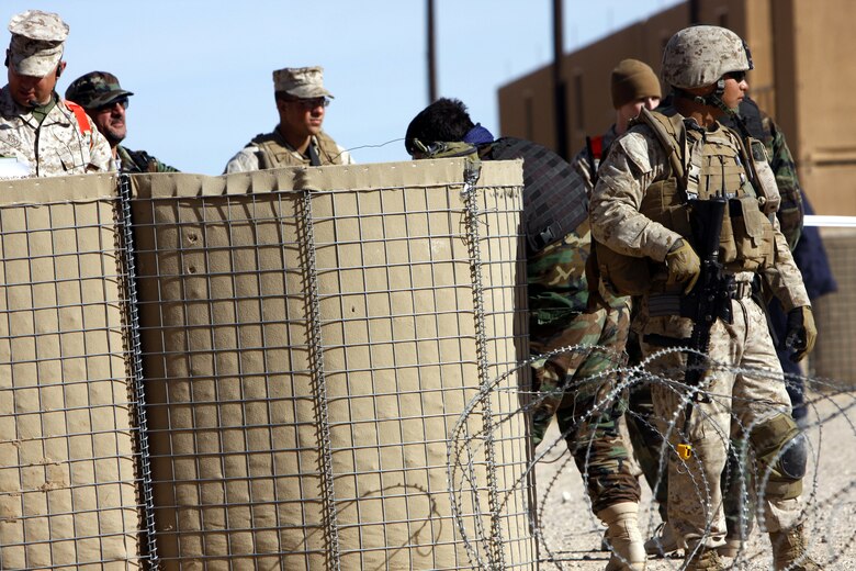 Cpl. Ramonanthony Ogo [right], an administrative clerk with Police Mentor Team 2, 3rd Battalion, 3rd Marine Regiment, based out of Marine Corps Base Kaneohe Bay, Hawaii, stands post at Combat Center Range 220 as Afghan police and others patrol the compound March 16.