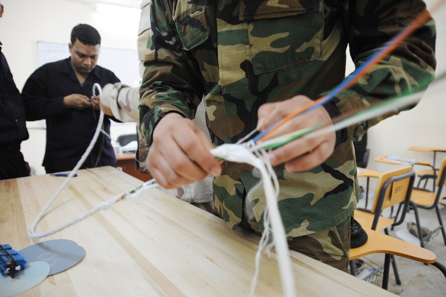 Iraqi military students participating in a cable and antenna maintenance class Feb. 13, 2010, unravel a long cable to separate what is inside.  The course is being taught by Staff Sgt. Gary Graf, an 821st Expeditionary Training Squadron cable and antenna maintenance instructor at Camp Taji, Iraq. During the 42-day course, Iraqi military students learn about theories, splicing cable and the improved capabilities that fiber optics can bring. Sergeant Graf is deployed to the 821st ETS from Sheppard Air Force Base, Texas. (U.S. Air Force photo/Master Sgt. Trish Bunting)