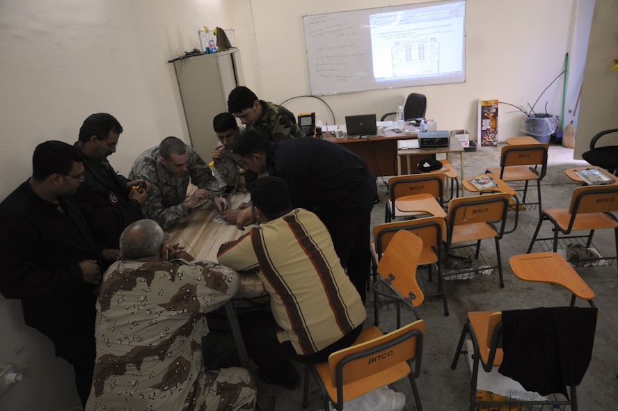 Staff Sgt. Gary Graf, an 821st Expeditionary Training Squadron cable and antenna maintenance instructor at Camp Taji, Iraq, gathers his students around a table as he demonstrates some of the characteristics of fiber optics Feb. 13, 2010. During the 42-day a fiber optics maintenance course, Iraqi military students learn about theories, splicing cable and the improved capabilities that fiber optics can bring. Sergeant Graf is deployed to the 821st ETS from Sheppard Air Force Base, Texas. (U.S. Air Force photo/Master Sgt. Trish Bunting)