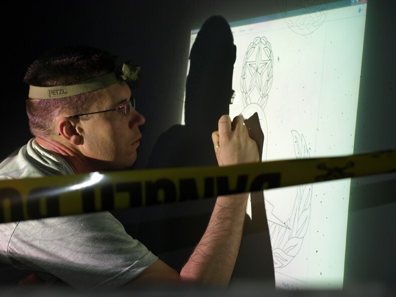 Tech. Sgt. Eric Eberhard, EOD technician in the 419th Fighter Wing, works on a memorial wall that he designed while deployed to Kirkuk Regional Air Base, Iraq. The wall, which was unveiled at a ceremony last month, honors three fallen Iraqi comrades. (Courtesy photo)