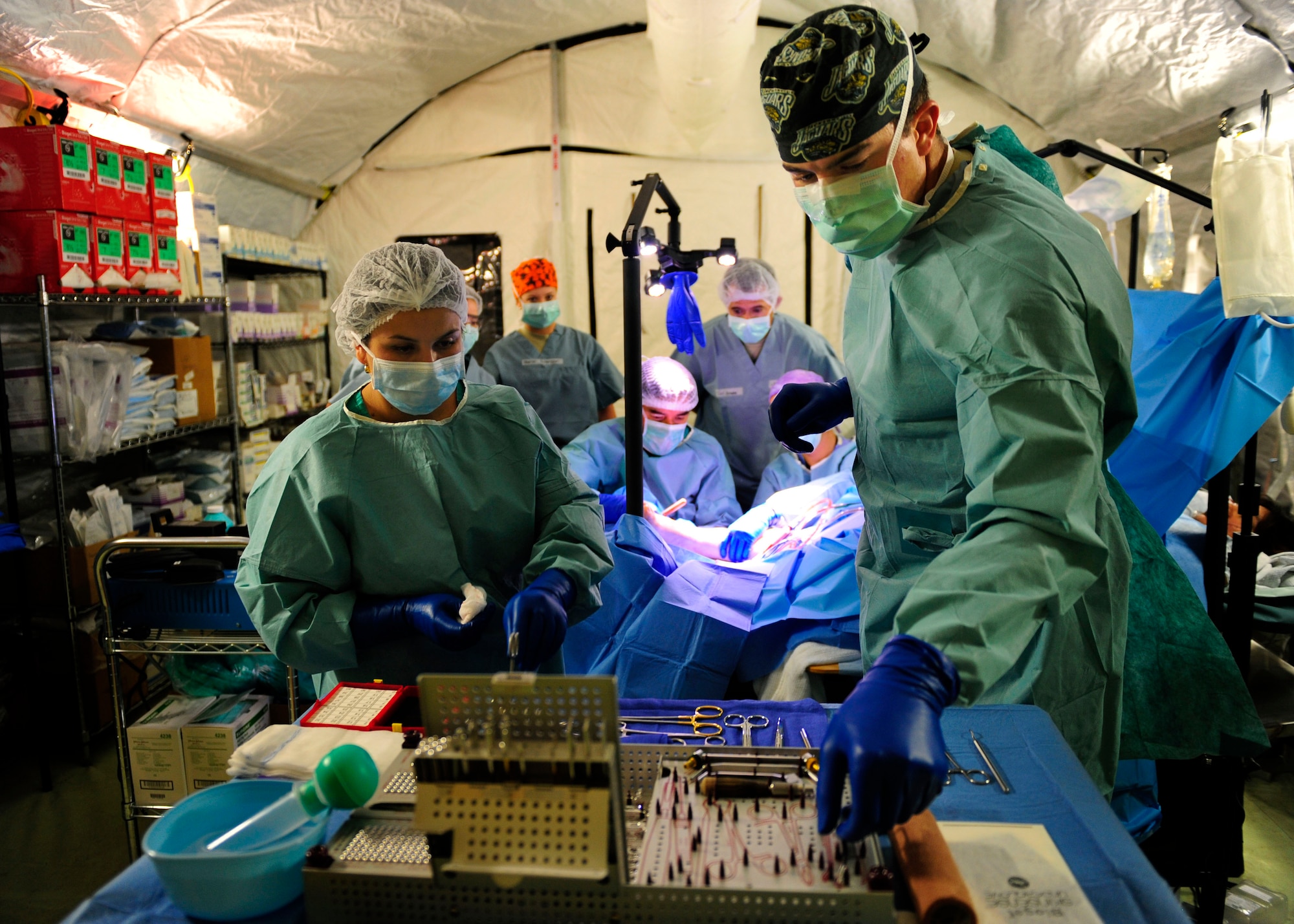 A Chilean surgical technician and Senior Airman Alexander Balock reach for instruments during the first surgery at the expeditionary medical hospital March 15, 2010, in Angol, Chile. The local hospital in Angol, a city southeast of Conception, Chile, was deemed structurally unsound as a result of an 8.8-magnitude earthquake Feb. 27. With the nearest operation ward more than 40 miles away, and many other local hospitals overwhelmed with casualties following the earthquake, local Chilean officials requested assistance from U.S. forces to help with primary care capabilities. Airman Balock is a surgical technician from the 81st Medical Surgical Squadron at Keesler Air Force Base, Miss. (U.S. Air Force photo/Senior Airman Tiffany Trojca)