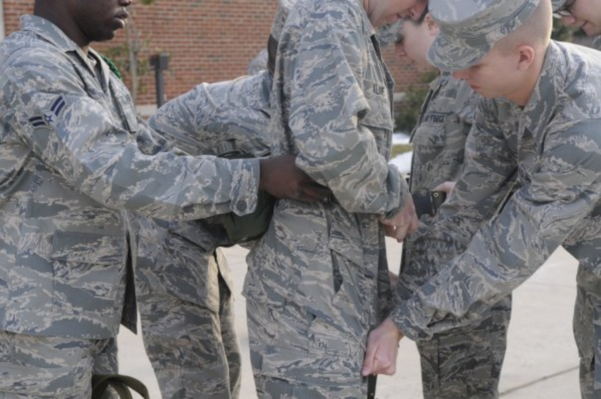 United States Air Force Honor Guard technical school trainees help each other put on their canteen belts, Feb. 22, 2010, outside of the Honor Guard dorms on Bolling Air Force Base, D.C. While wearing the canteen belts, trainees' uniforms must be pulled and creased properly in order to contain a professional appearance. (U.S. Air Force photo by Senior Airman Marleah Miller)