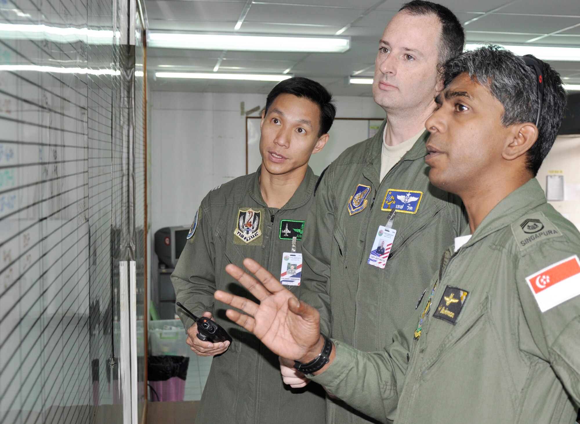Republic of Singapore Air Force Master Warrant Officer Andre Ravi, discusses scheduling issues with U.S. Air Force Capt. Jeff Watts and Royal Thai Air Force Wing Commander Arnon Charusombat March 11, 2010 during Cope Tiger 2010 in Thailand. The airmen have worked together during the past four Cope Tiger exercises deconflicting airspace issues and tracking the flying schedule. (U.S. Air Force photo/Capt. Christy Stravolo)