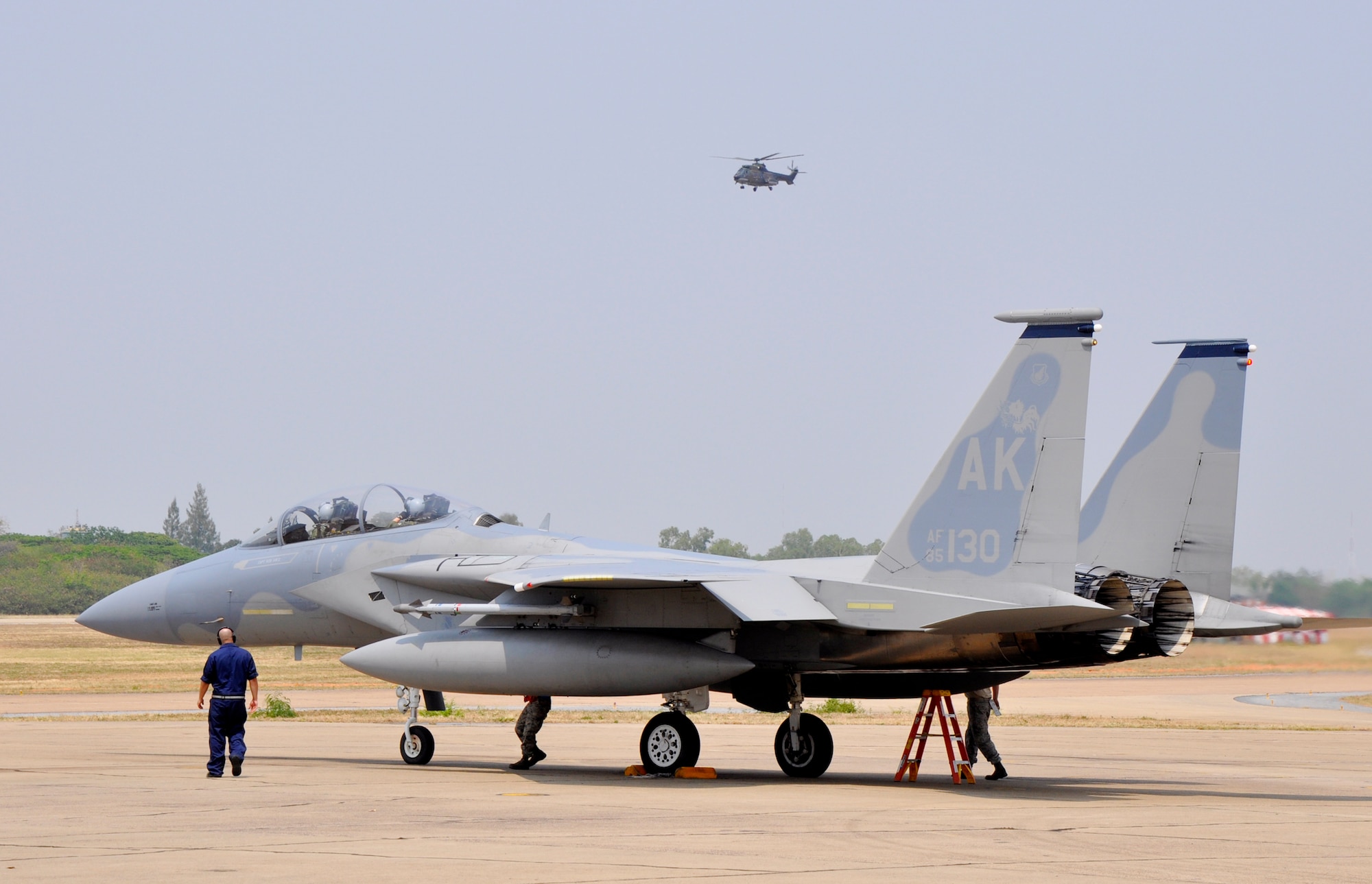 A Republic of Singapore Air Force Super Puma helicopter hovers overhead as a U.S. Air Force F-15 Eagle prepares to take off March 9, 2010, at Korat Royal Thai Air Force Base, Thailand. U.S., Singapore and Thai air forces are participating in Cope Tiger, a multilateral aerial large force exercise that takes place annually. (U.S. Air Force photo/Capt. Christy Stravolo)