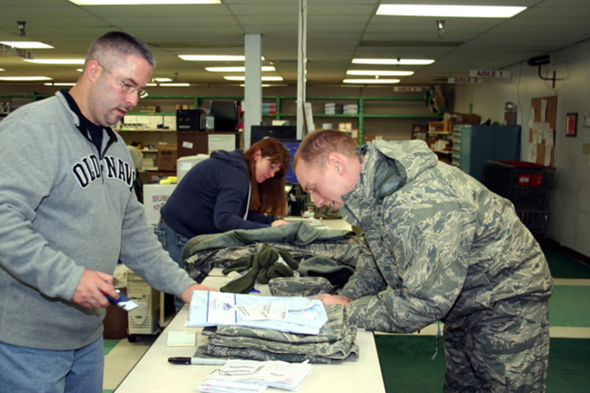 GRISSOM AIR RESERVE BASE, Ind., -- Staff Sgt. Stephen Heidrich, right, an instrument technician with the 434th Aircraft Maintenance Squadron signs for a clothing order at the individual equipment unit (referred to as IEU) while Chad Malott, left, a DMS supply warehouseman checks the order.   Store clerk Amy Fenton, center background, processes receipts from earlier customers.  (U.S. Air Force photo/Staff Sgt. Chris Bolen)