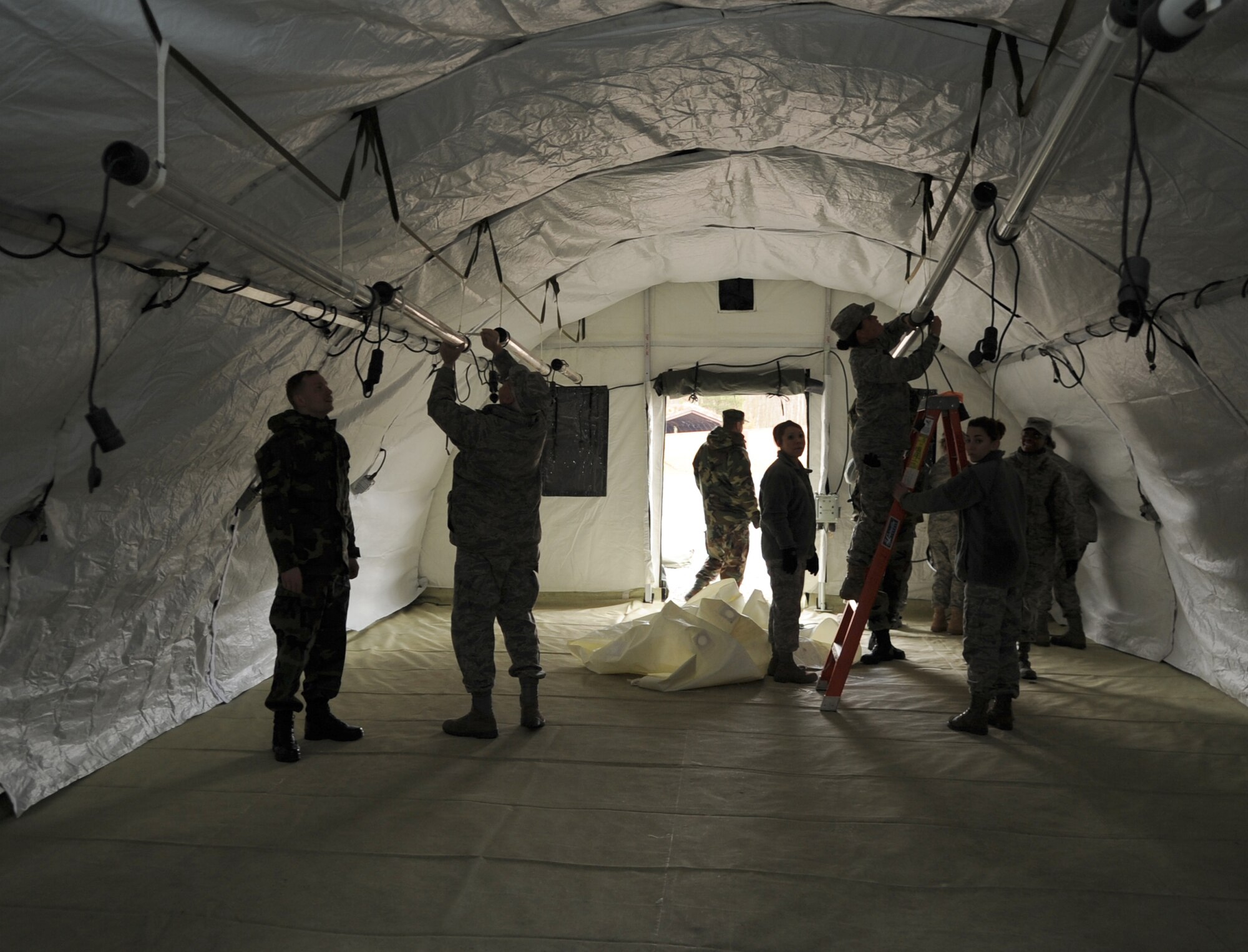U.S. Air Force medical members participating in the Expeditionary Medical Support (EMEDS) Mobile Course set up lights and electricity needed for mission readiness during the tent build up portion of training, Ramstein Air Base, Germany, March 15, 2010. The EMEDS course teaches and evaluates corps specific field situations as well as offers updates in Air Force Medical Service concept of operations and doctrine.  It also teaches setup and packing out of a field EMEDS compound, deployed operations, field medical, nursing and operational support equipment proficiency, field exercises to both emphasize and evaluate learning of concepts taught. (U.S. Air Force photo by Airman 1st Class Caleb Pierce)