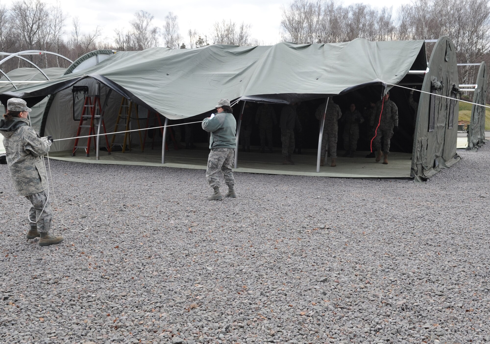 U.S. Air Force medical members participating in the Expeditionary Medical Support (EMEDS) Mobile Course pull a tarp over a tent during the tent build up portion of training, Ramstein Air Base, Germany, March 15, 2010. The EMEDS course teaches and evaluates corps specific field situations as well as offers updates in Air Force Medical Service concept of operations and doctrine.  It also teaches setup and packing out of a field EMEDS compound, deployed operations, field medical, nursing and operational support equipment proficiency, field exercises to both emphasize and evaluate learning of concepts taught. (U.S. Air Force photo by Airman 1st Class Caleb Pierce)