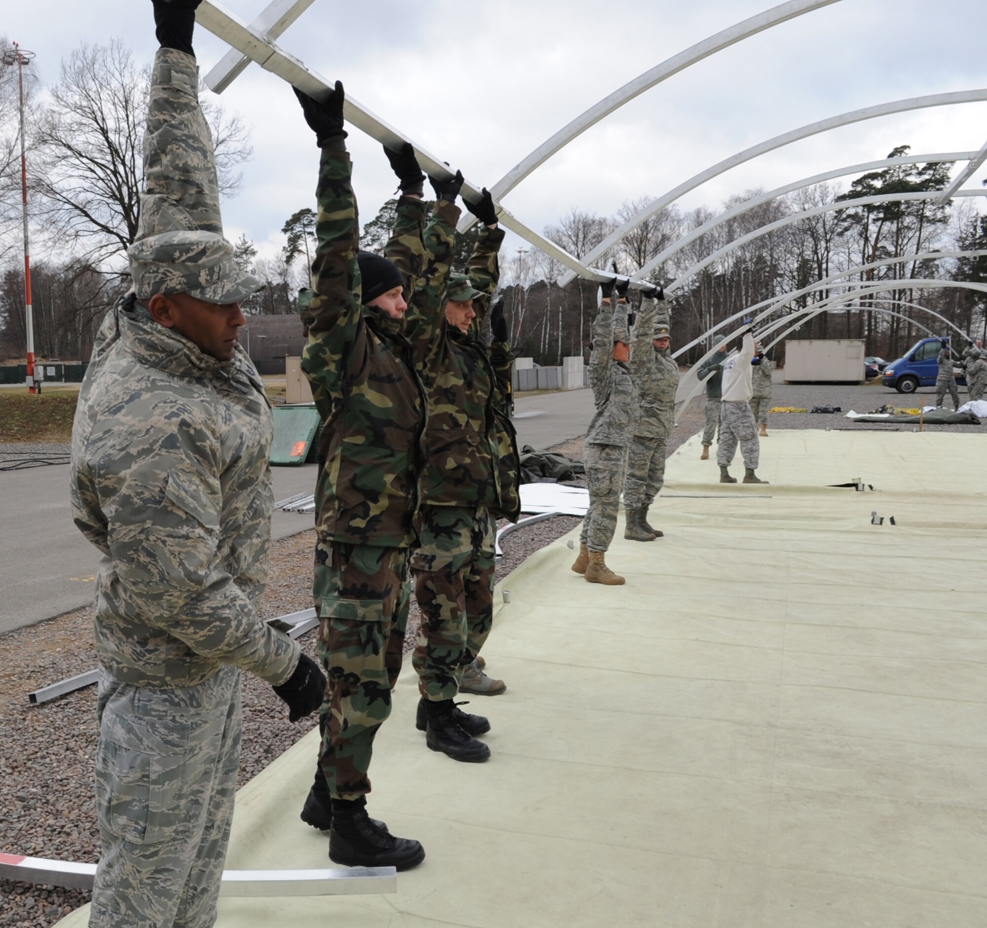 U.S. Air Force medical members participating in the Expeditionary Medical Support (EMEDS) Mobile Course raise a tent structure after assembling during the tent build up portion of EMEDS, Ramstein Air Base, Germany, March 15, 2010. The EMEDS course teaches and evaluates corps specific field situations as well as offers updates in Air Force Medical Service concept of operations and doctrine.  It also teaches setup and packing out of a field EMEDS compound, deployed operations, field medical, nursing and operational support equipment proficiency, field exercises to both emphasize and evaluate learning of concepts taught. (U.S. Air Force photo by Airman 1st Class Caleb Pierce)