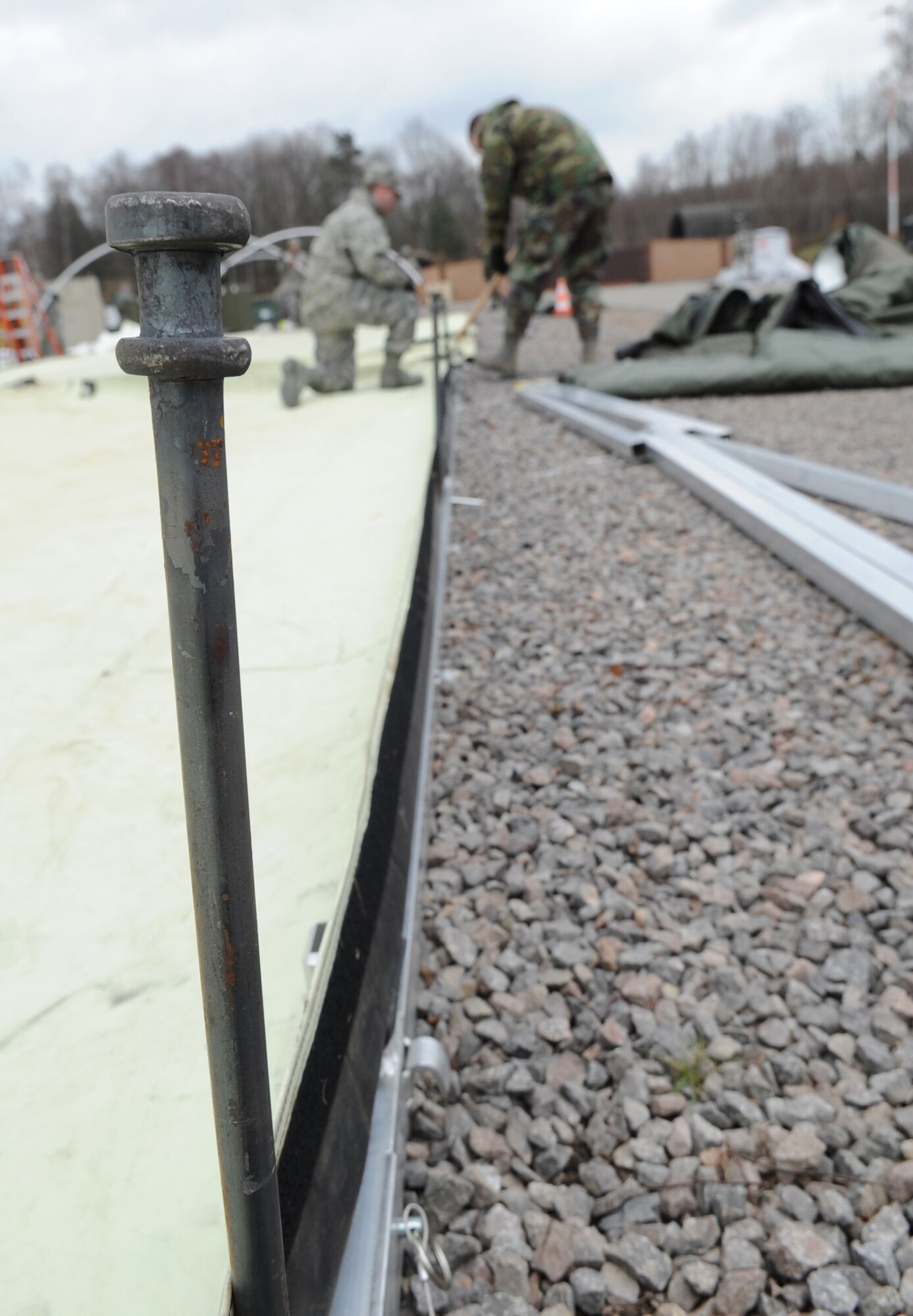 U.S. Air Force medical members participating in the Expeditionary Medical Support (EMEDS) Mobile Course drive tent pegs into the ground to keep frames stabilized during the tent build up portion of EMEDS, Ramstein Air Base, Germany, March 15, 2010. The EMEDS course teaches and evaluates corps specific field situations as well as offers updates in Air Force Medical Service concept of operations and doctrine.  It also teaches setup and packing out of a field EMEDS compound, deployed operations, field medical, nursing and operational support equipment proficiency, field exercises to both emphasize and evaluate learning of concepts taught. (U.S. Air Force photo by Airman 1st Class Caleb Pierce)