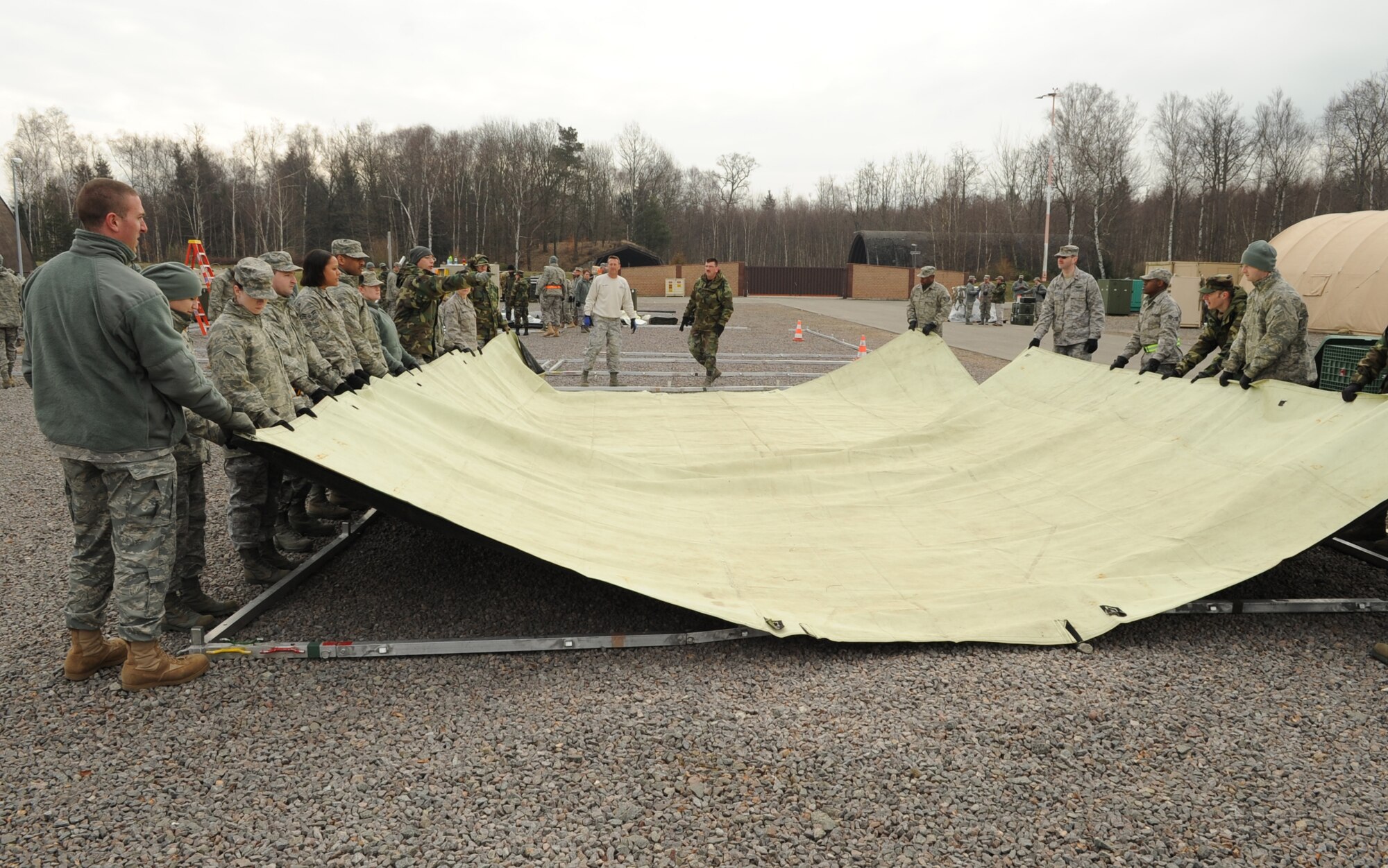 U.S. Air Force medical members participating in the Expeditionary Medical Support (EMEDS) Mobile Course spread out tent tarp over frames during the tent build up portion of EMEDS, Ramstein Air Base, Germany, March 15, 2010. The EMEDS course teaches and evaluates corps specific field situations as well as offers updates in Air Force Medical Service concept of operations and doctrine.  It also teaches setup and packing out of a field EMEDS compound, deployed operations, field medical, nursing and operational support equipment proficiency, field exercises to both emphasize and evaluate learning of concepts taught. (U.S. Air Force photo by Airman 1st Class Caleb Pierce)
