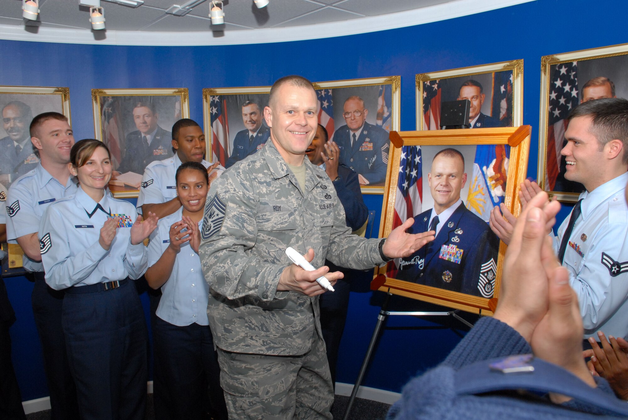 Air Force Chief Master Sgt. James Roy signs his painting that will be hung in the Enlisted Heritage Hall. Local members of the Single Airman Working Board who are developing programs for single Airmen in the Air Force greeted, and then briefed, Chief Roy during his visit to Maxwell.(Air Force photo/Bennett Rock)