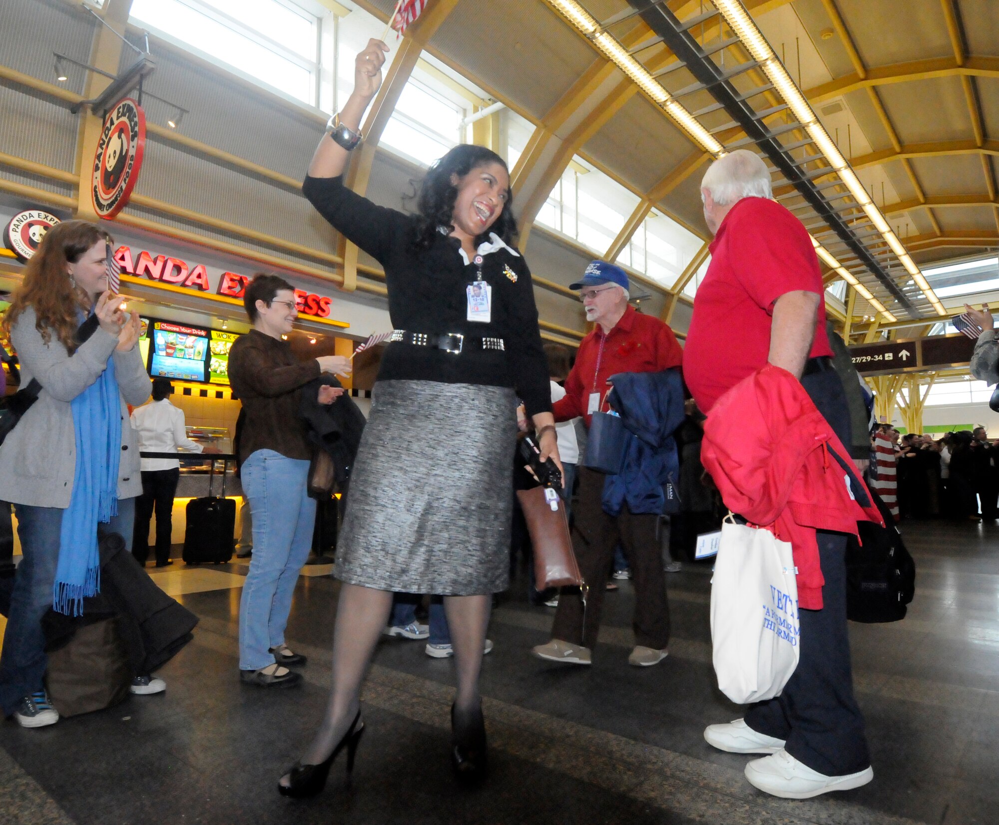 World War II Honor Flight veterans greet a line of supporters cheering and waving American flags at Ronald Reagan Washington National Airport March 10. More than 200 active duty military members gathered to greet the 256 incoming veterans. Since May 2005, Honor Flight Network has transported more than 36,000 World War II, Korea and Viet Nam veterans to Washington, D.C., for a one-day trip that includes sightseeing at all of the  memorials built in honor of the veterans. (U.S. Air Force photo by Airman 1st Class Susan Moreno)