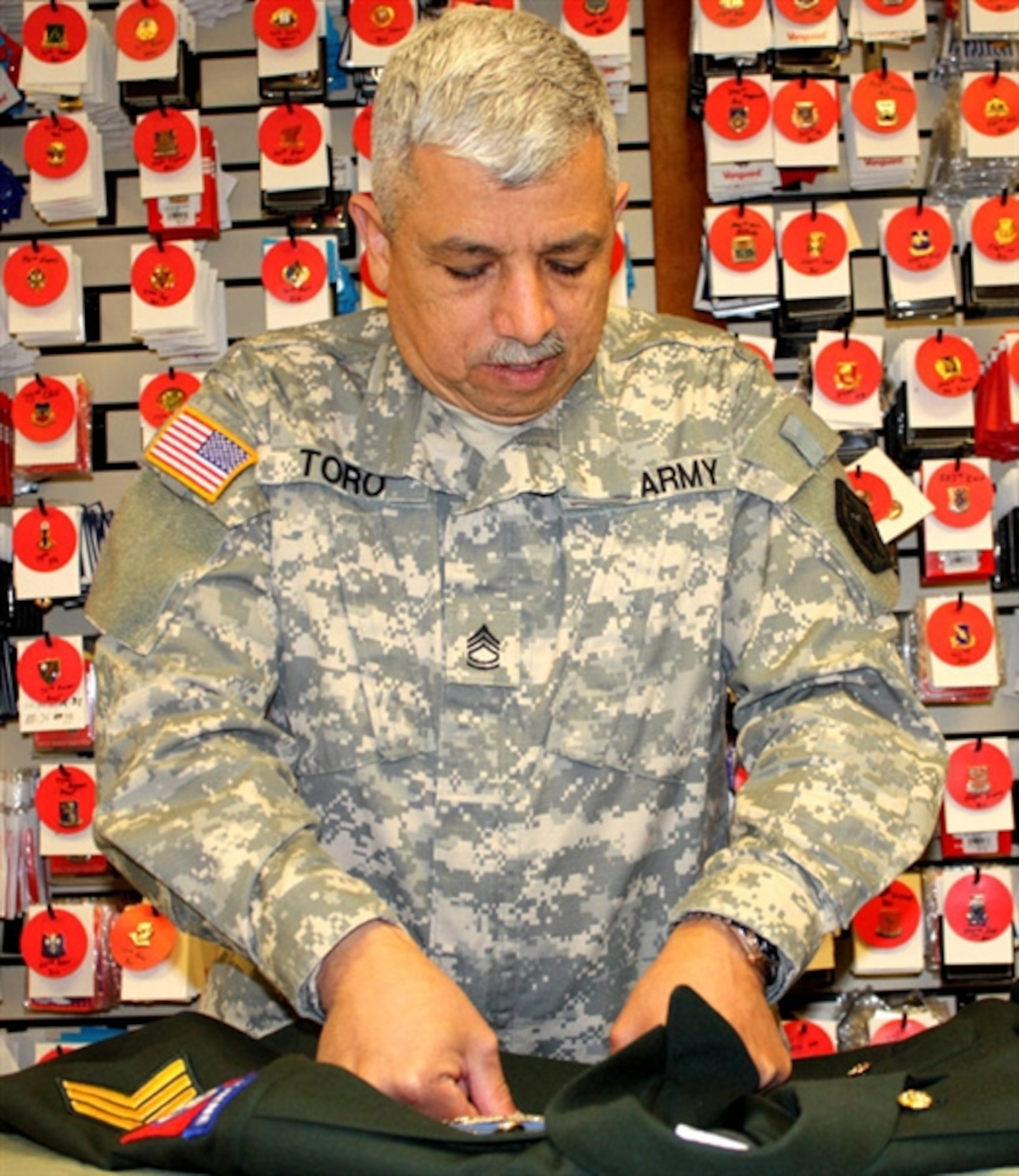 Army Sgt. 1st Class Jimmy Toro clips a ribbon rack onto a new dress uniform at the uniform shop of the Air Force Mortuary Affairs Operations Center at Dover Air Force Base, Del., Feb. 23. Toro prepares uniforms for fallen soldiers’ remains. (DoD photo by Elaine Wilson)  