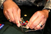 Army Sgt. 1st Class Jimmy Toro measures the distance between an insignia and ribbon rack while preparing a uniform at the uniform shop of the Air Force Mortuary Affairs Operations Center at Dover Air Force Base, Del., Feb. 23. Toro prepares uniforms for fallen soldiers’ remains. (DoD photo/Elaine Wilson)  
