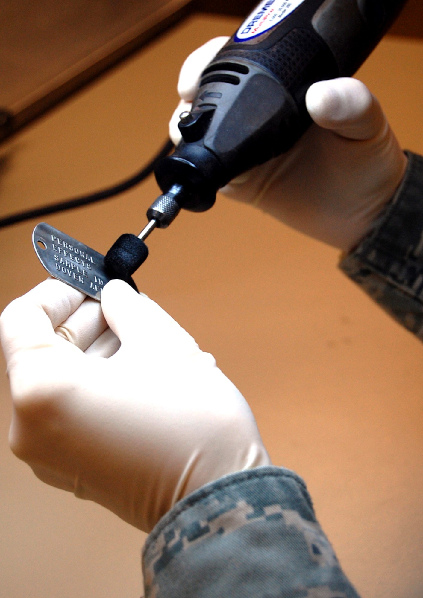 Master Sgt. Tracy Bailey cleans a dog tag at the personal effects section of the Air Force Mortuary Affairs Operations Center at Dover Air Force Base, Del., Feb. 25. It’s Bailey’s job to clean the personal belongings that arrive with a fallen servicemember’s remains. The belongings are then returned to family members. (U.S. Air Force photo)  
