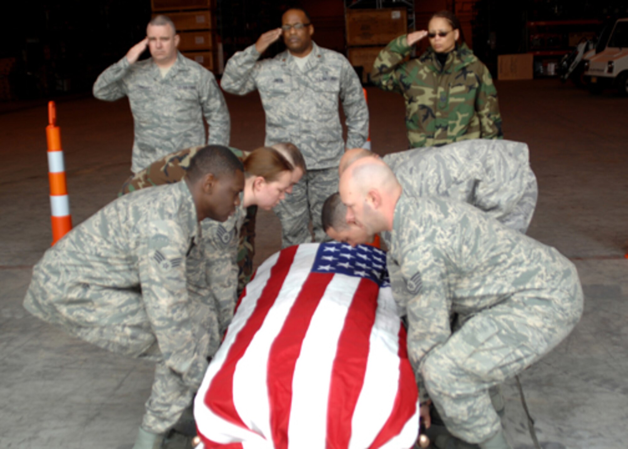 GRISSOM AIR RESERVE BASE, Ind. -- (from left) Tech. Sgt. Kevin Connelly, aerial port specialsit, Chaplain (Maj) Obadiah Smith, and Master Sgt. Trudy Burnett, chaplain's assistant, render salutes during dignified transfer training at Grissom.  An empty flag-draped transfer case was utilized during the training session.  (U.S. Air Force photo/Senior Airman Carl Berry)