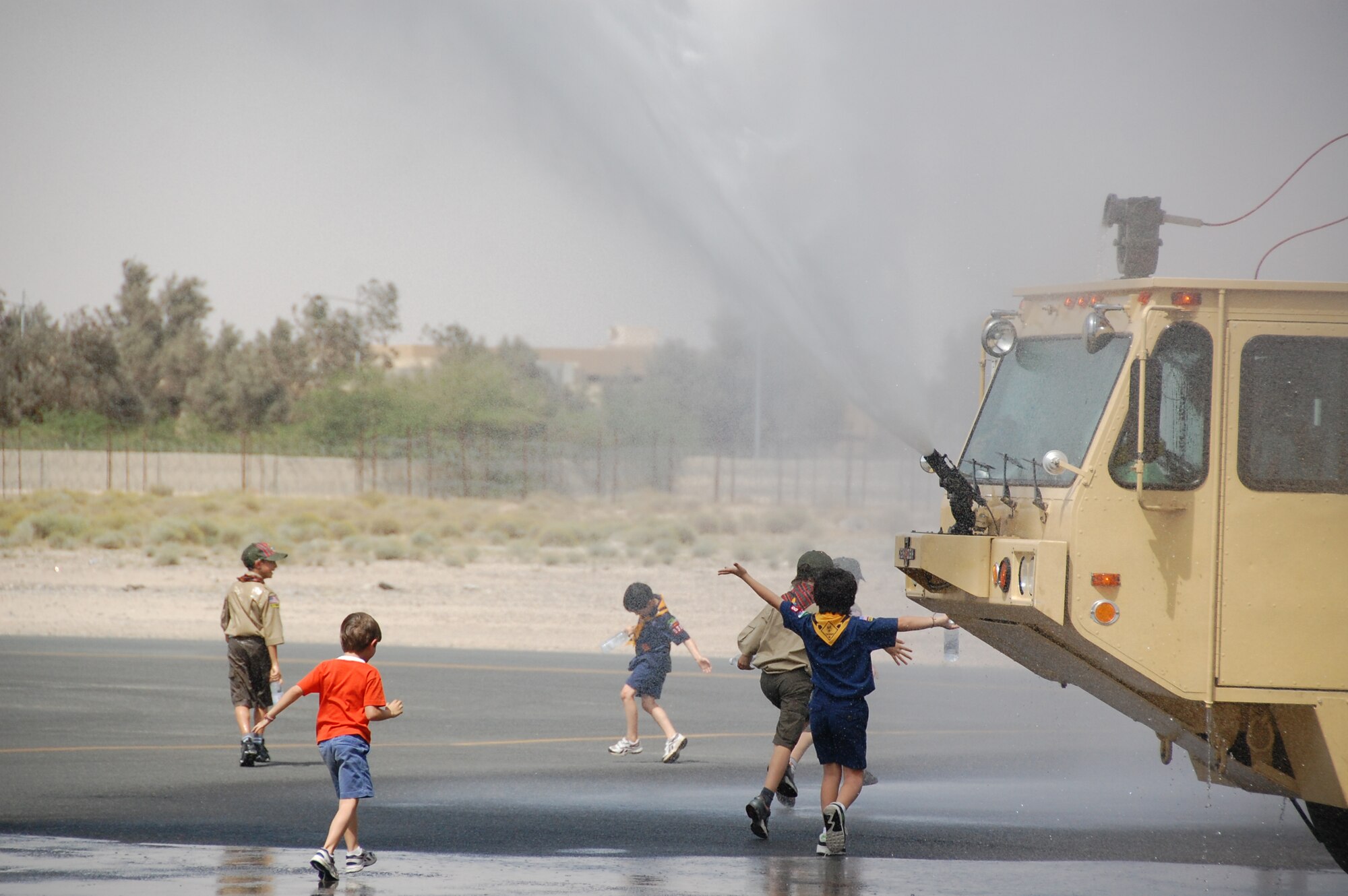 Local Boy Scouts and Cub Scouts cool off in the 100-degree heat after a 386th Expeditionary Civil Engineer Squadron Fire Department demonstration March 13, 2010 as part of a tour of the air base in Southwest Asia. During the tour, the Scouts, who reside near the undisclosed location, visited with EOD, Fire Department and Military Working Dog Airmen; walked through C-130 and C-17 static displays on the flightline and ate lunch at the dining facility. (U.S. Air Force Staff Sgt. Lindsey Maurice/Released)