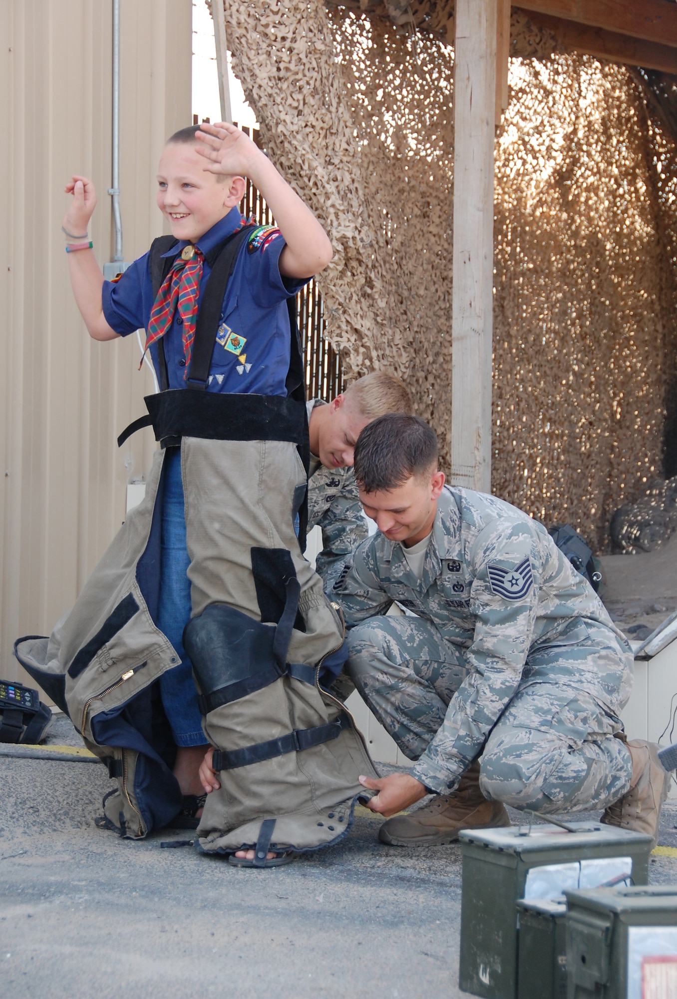 U.S. Air Force Tech. Sgt. David McMaster and Senior Airman Luke Wagner, both of the 386th Expeditionary Civil Engineer Squadron Explosive Ordnance Disposal team, dress Tadhg Oude Essink, a local Cub Scout, in a bomb suit during the troop's tour of the 386th Air Expeditionary Wing March 13, 2010 at an air base in Southwest Asia. The Boy Scouts and Cub Scouts, who reside near the undisclosed location, were able to visit with EOD, Fire Department and Military Working Dog team members as well as walk through C-130 and C-17 static displays on the flightline during the tour. (U.S. Air Force Staff Sgt. Lindsey Maurice/Released)