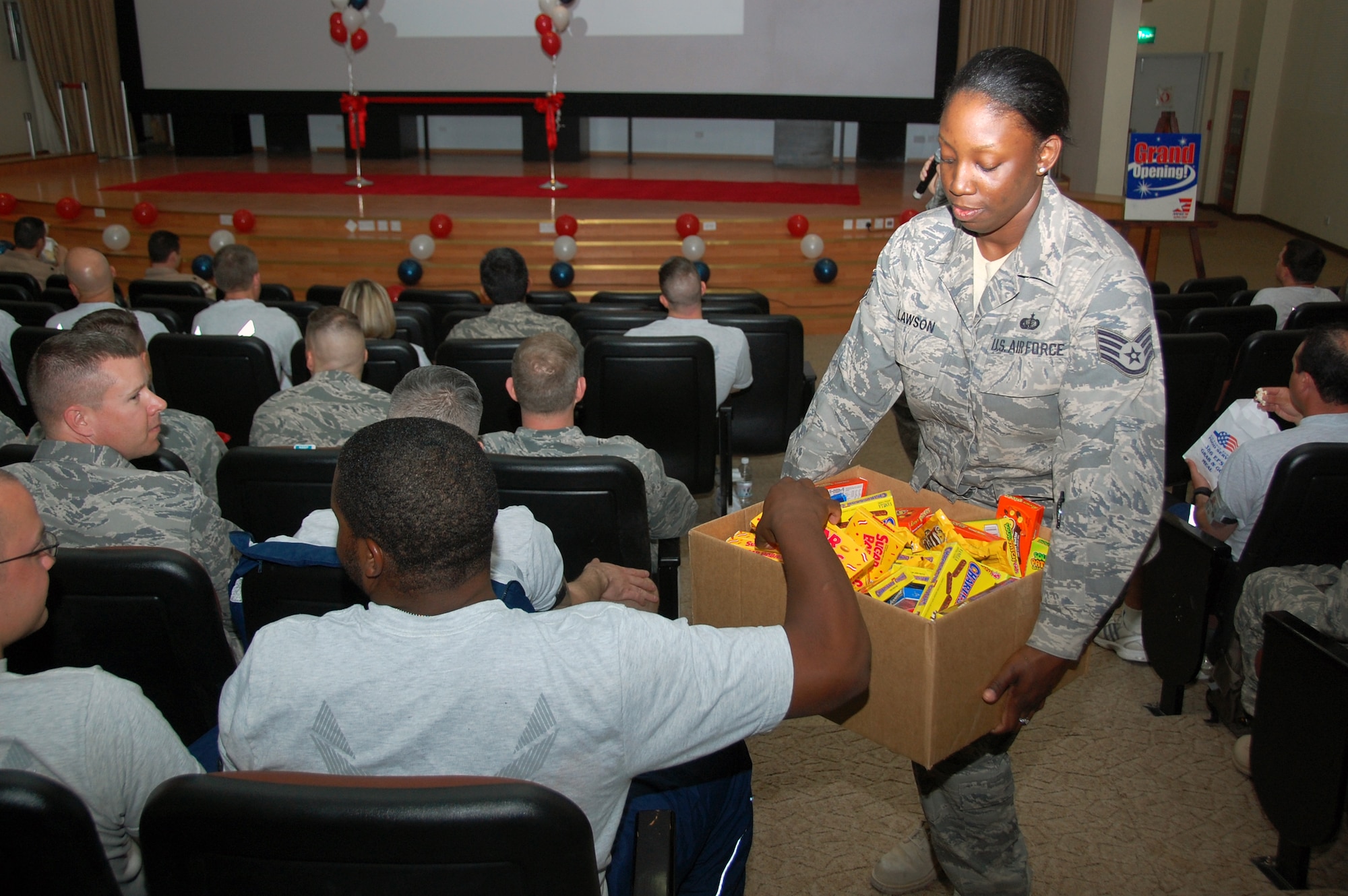 U.S. Air Force Staff Sgt. Tinisha Lawson, 386th Expeditionary Force Support Squadron, passes out candy to a movie trivia contest winner during the base theater grand opening celebration March 12, 2010 at an air base in Southwest Asia. (U.S. Air Force photo by Staff Sgt. Lindsey Maurice/Released)