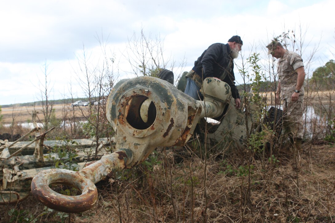 Jack Tagmyer, manager of the Auto Body Hobby Shop and Chief Warrant Officer 2 Chad Weidner, maintenance officer with 2nd Combat Engineer Battalion, 2nd Marine Division, inspect the abandoned Soviet 122mm howitzer D-30 during its recovery operation, March 16. Discovered by retired Col. Terry Cahill two years ago, the howitzer will be refurbished and donated to a local organization as an Iraqi War memorial.