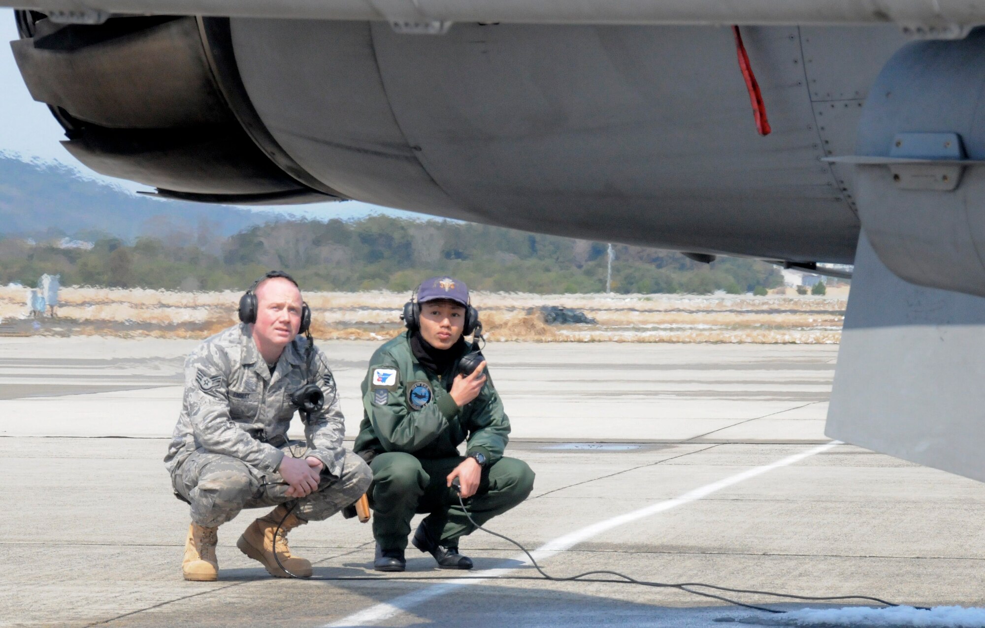 TSUIKI AIR BASE, Japan -- Staff Sgt. Robert Ensley, 35th Aircraft Maintenance Squadron crewchief, waits to conduct a pre-flight inspection with Japan Air Self-Defense Force crewchief Senior Airman Naoki Yamashita March 11. As part of an aviation training relocation, crewchiefs from the U.S. and Japan had the chance to experience flightline operations with each other. (U.S. Air Force photo/Staff Sgt. Rachel Martinez)