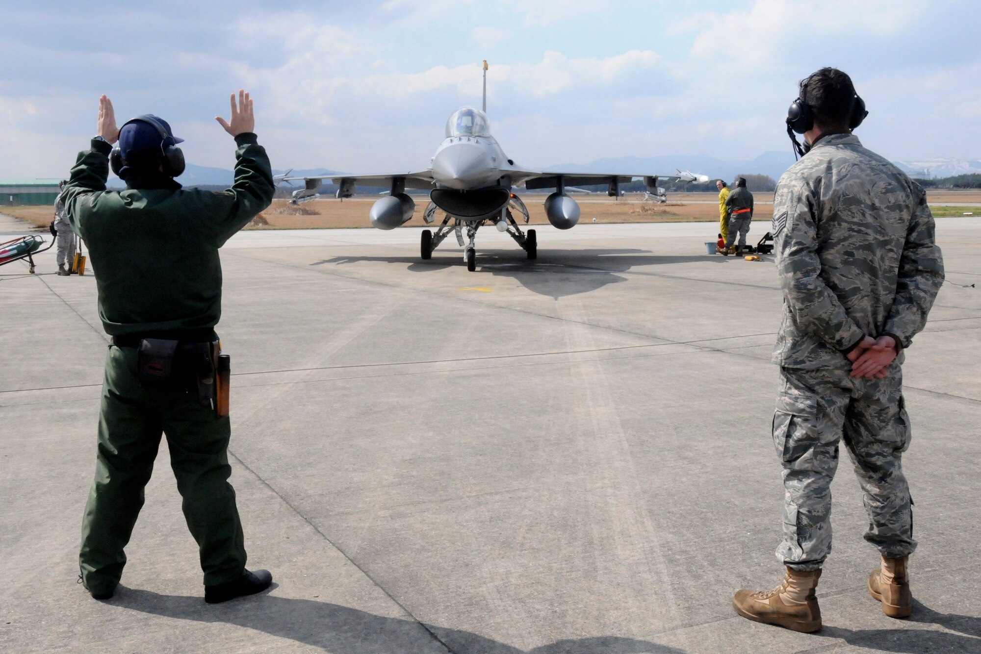 TSUIKI AIR BASE, Japan -- Japan Air Self-Defense Force Senior Airman Naoki Yamashita, F-15 crewchief, marshals in an F-16 Fighting Falcon under the watch of Staff Sgt. Staff Sgt. Christopher Audet, 35th Aircraft Maintenance Squadron crewchief, during an aviation training relocation exercise March 11. The two crewchiefs were able to launch and recover jets from the other nation's air force as part of a cross-familiarization program. (U.S. Air Force photo/Staff Sgt. Rachel Martinez)