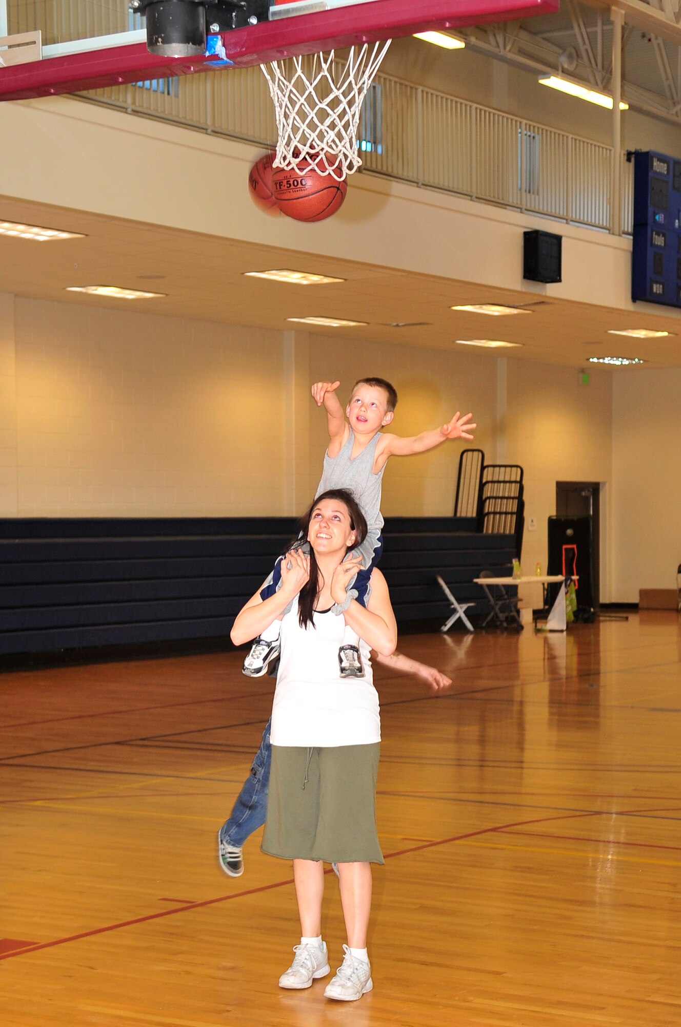 BUCKLEY AIR FORCE BASE, Colo. -- Laura Mellon, a mom from Team Buckley, puts son Butchie Mellon on her shoulders to shoot a basket during the Fit Factor Family event March 13. (U.S. Air Force photo by Airman 1st Class Manisha Vasquez) 