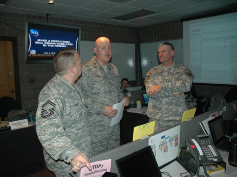 Maj. Gen. David Sprynczynatyk, the North Dakota adjutant general, visits North Dakota National Guard personnel, Maj. Martin Tonn, center, and Senior Master Sgt. Tim Laney, as they work in the emergency operations center (EOC) Mar. 15, Fargo, N.D.  The EOC personnel are directing flood fighting activities of National Guard members on the front lines of the rising water.  The North Dakota National Guard plan calls for 300-400 personnel to participate in flood fighting activities like driving heavy equipment, sandbagging, traffic control, and barrier assembly.     

