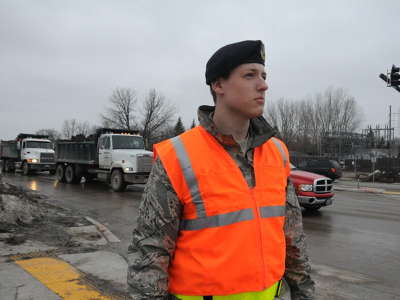 Staff Sgt. Brandon Berce, of the 119th Security Forces Squadron, waits and watches for Fargo city police car escorts of sandbag trucks Mar. 15, at a North Dakota National Guard traffic control point (TCP).  Berce is tasked with stopping traffic at the intersection so that the truck carrying flood fighting sandbags and the police escort can easily pass through the intersection, allowing the sandbags to arrive quickly at its’ destination on the front lines of the flood fight.
