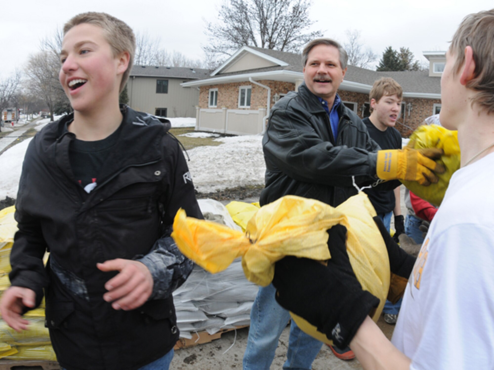 N.D. Gov. John Hoeven joins a group of Fargo South High School students March 16 as they pass sandbags from pallets into backyards of houses along the Red River in south Fargo, N.D. The sandbags are being used to create flood barriers in an effort to protect homes from the rising water of the Red River. (DoD photo by Senior Master Sgt. David H. Lipp) (Released)