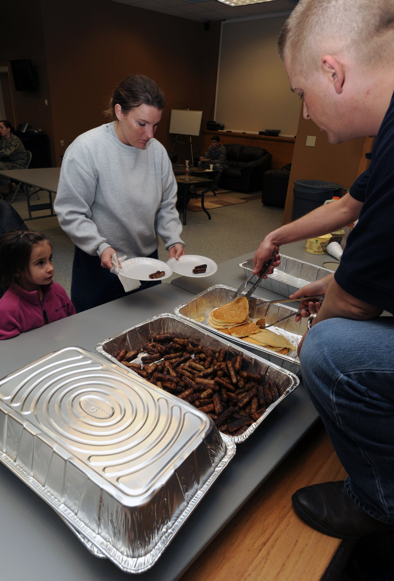 Master Sgt. John Smith, 319th Civil Engineer Squadron first sergeant, serves pancakes and sausages to Staff Sgt. Shawna Chiasson, 319th CES, and her daughter, Olivia Chiasson, March 16 at Sven’s Den on Grand Forks Air Force Base, N.D.  The base’s first sergeants held a breakfast to raise money for Airmen. (U.S. Air Force photo by Airman 1st Class Amber Price)