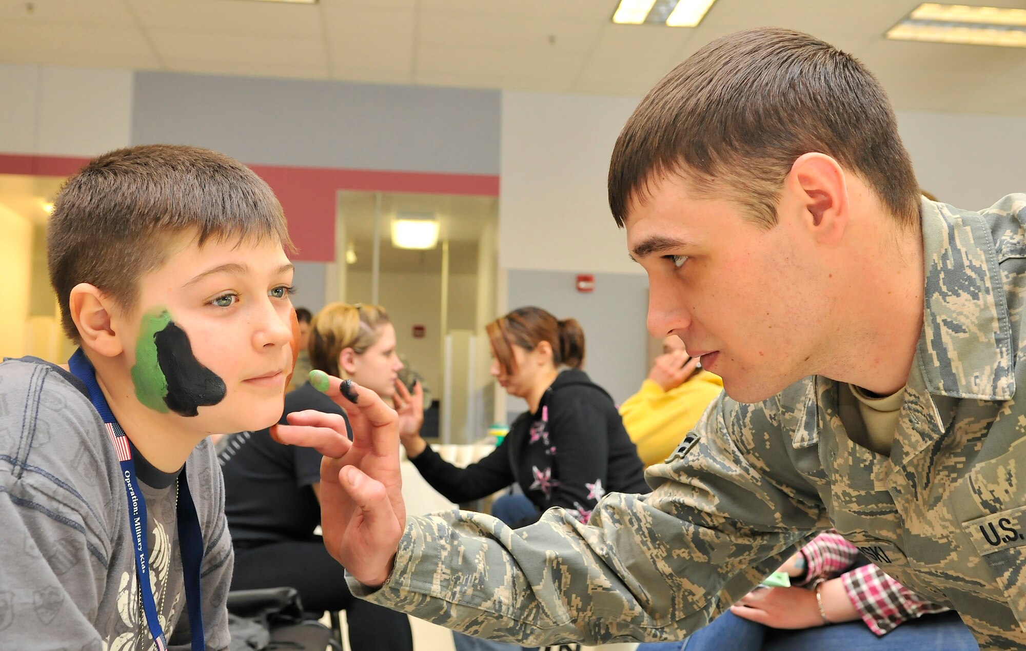 Airman 1st Class Andrew Marowski applies camouflage paint to Storm Woodin's during Operation Bug Out at the Joint Mobility Center Mar. 12, 2010, Eielson Air Force Base, Alaska. Operation Bug Out is a venue for children to experience what is like for their loved one to deploy. Airman Marowski is assigned to the 354th Logistics Readiness Squadron. Storm's father, Master Sgt. Robert Woodin, is the 354th Security Forces first sergeant. (U.S. Air Force photo/Staff Sgt. Christopher Boitz)