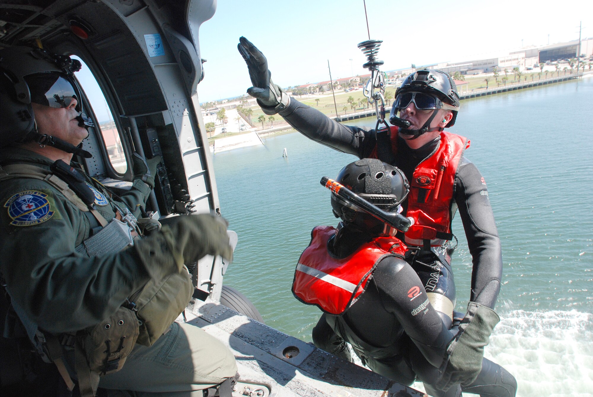 PATRICK AIR FORCE BASE, Fla. -  Chief Master Sgt. Lazaro Ibarra (left) helicopter flight engineer, 301st Rescue Squadron here, hoists Capt. Niul Manske, combat rescue officer, and Staff Sgt. Carl Jensen, both pararescumen from the 304th Rescue Squadron, Portland, Ore., from the Banana River into this HH-60G Pave Hawk helicopter during water-rescue training near Patrick Air Force Base. The two-man hoists are a small part of the overall training for the PJs. The 304th RQS is a geographically separated unit of the 920th RQW. The Portland PJs normally specialize in snow-capped mountain rescues whereas here the mountain men are getting a dose of warm salty air. All of these men are Air Force Reservists with the 920th Rescue Wing.  (U.S. Air Force photo/Staff Sgt. Leslie Kraushaar)