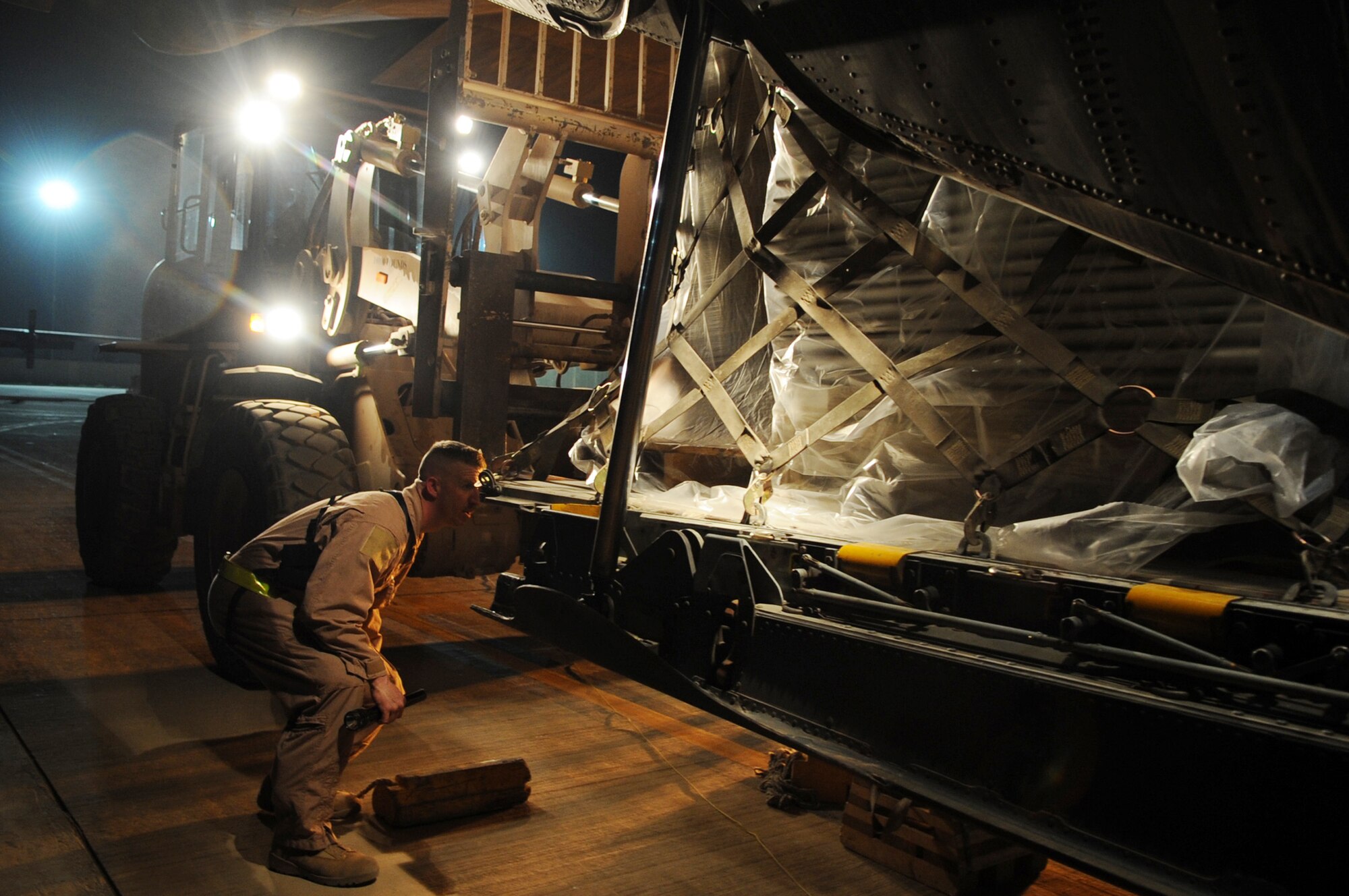 A flight engineer assigned to the 777th Expeditionary Aircraft Maintenance Unit helps guide a forklift to place a pallet in a C-130E Hercules prior to its last combat mission March 6, 2010, at Joint Base Balad, Iraq. (U.S. Air Force photo/Senior Airman Brittany Y. Bateman)