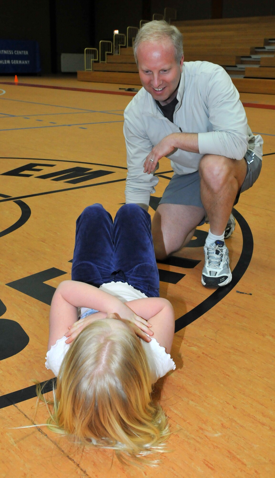 SPANGDAHLEM AIR BASE, Germany – Lt. Col. John Caye, 52nd Medical Group health facilities chief, helps his 7-year-old daughter Signe perform sit-ups during a family circuit training class March 12 in the Skelton Memorial Fitness Center. Classes are held 6-7 p.m.  every Friday. Children 6 years-old and older are allowed to participate. (U.S. Air Force photo/Airman 1st Class Nick Wilson)