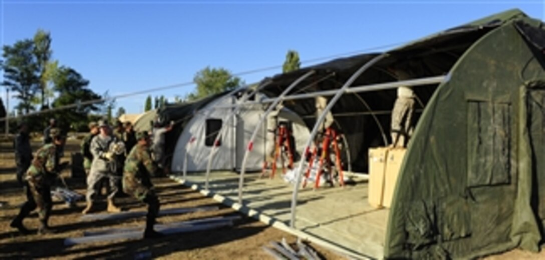 Chilean soldiers help U.S. airmen from an expeditionary medical support team pull the roof over a mobile hospital in Angol, Chile, on March 12, 2010.  The expeditionary medical support team is adding an additional operating room and three patient wards to the facility at the request of local Chilean medical officials.  The U.S. Air Force is assisting in the area in the wake of an 8.8-magnitude earthquake that struck the country on Feb. 27, 2010.  