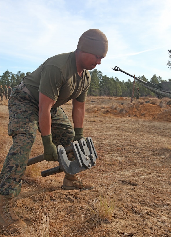 Lance Cpl. Richard J. Barron, a canoneer with 2nd Battalion, 10th Marine Regiment, 2nd Marine Division, removes the trident bar from an M777 Light Towed Howitzer during a month-long regimental field exercise called Rolling Thunder, aboard Fort Bragg, March 18, 2010. The bar is put on the gun each night after each day’s firing is over to prevent it from functioning, similar to switching the safety on a rifle.