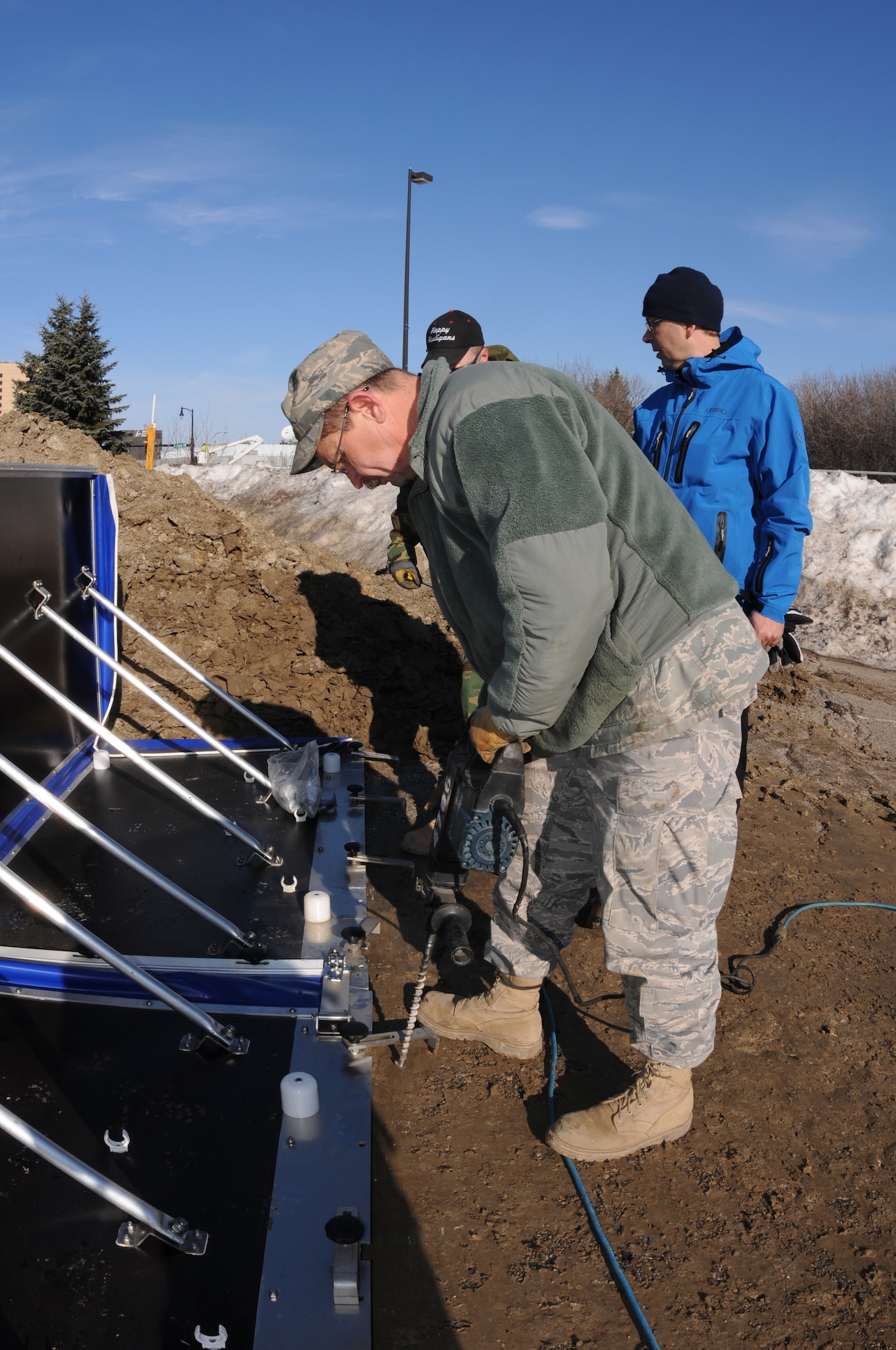 Senior Master Sgt. Scott Wagner, of the 119th Civil Engineer Squadron, drills a hole in pavement to secure an experimental AquaFence in place March 17 in Fargo, N.D. The AquaFence is being installed by the North Dakota Air National Guard for the City of Fargo as a test flood barrier to see if it might be effective for use in future flood protection.  (DoD photo by Senior Master Sgt. David H. Lipp) (Released)