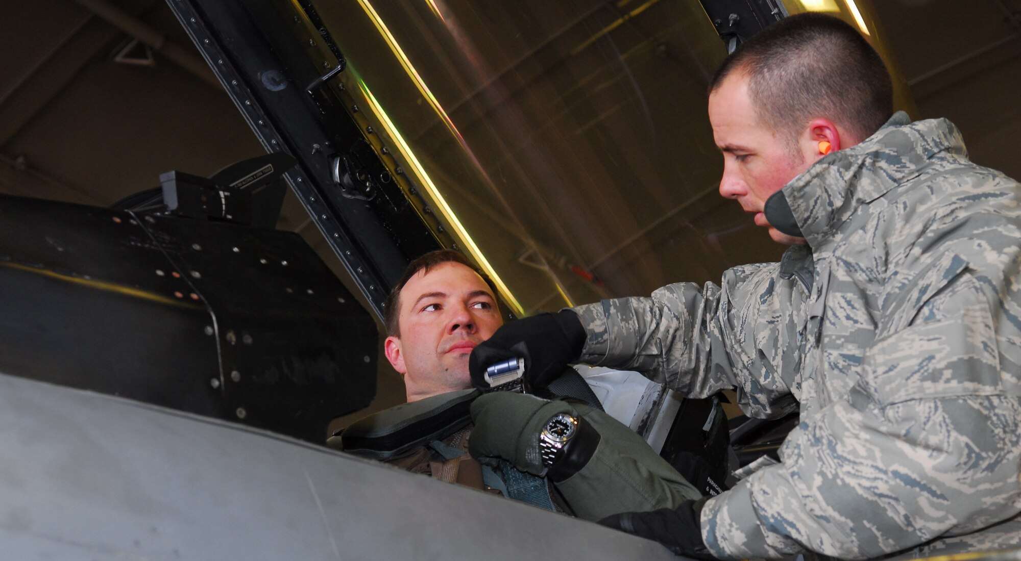 MISAWA AIR BASE, Japan – Staff Sgt. Donald Slayton, 13th Aircraft Maintenance Unit dedicated-crewchief, buckles Maj. Dylan Baumgartner, 35th Fighter Wing chief of wing inspections, into his seat prior to his training sortie March 16 in a hardened aircraft shelter. With a full load of internal fuel, the F-16 can withstand up to nine times the force of gravity. (U.S. Air Force photo/Staff Sgt. Phillip Butterfield)