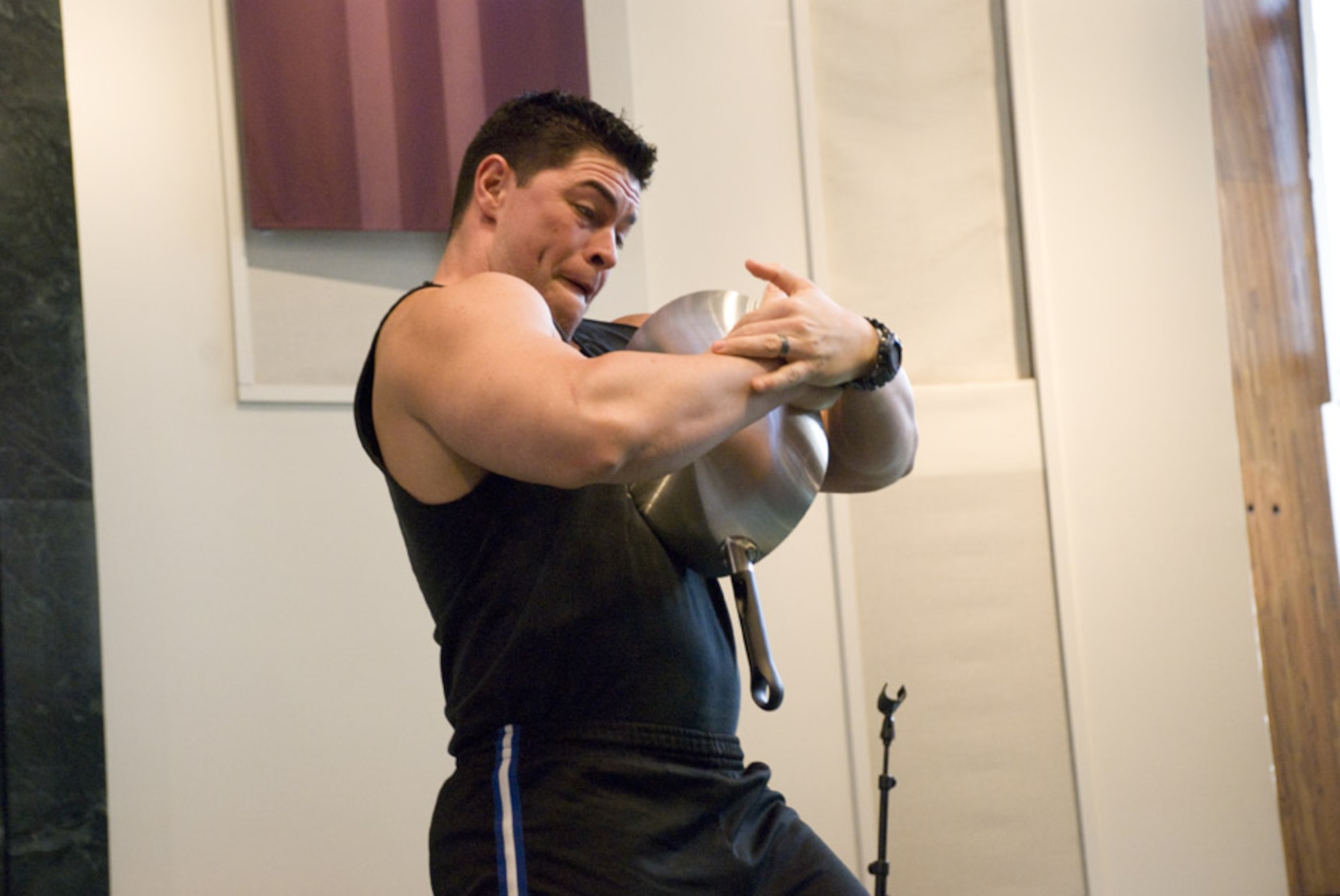 SCOTT AIR FORCE BASE, Ill. -- Team Impact member Cesar Arocha bends and rolls up a frying pan during the group’s performance at the Scott Chapel March 11, 2010, at Scott Air Force Base, Ill.  Team Impact’s performances combine a strongman show with motivational speaking. (U.S. Air Force photo by Steve Berry)