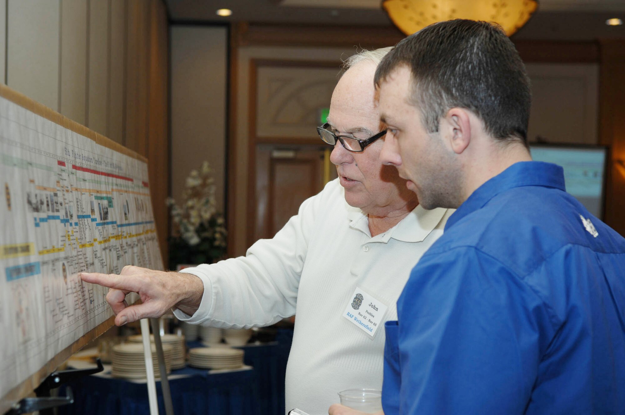 Lt. Col. John Peebles discusses the 55th Fighter Squadron history with Capt. Brian Hoose at a reunion breakfast, March 6, 2010, in Las Vegas. Colonel Peebles is a 55th FS "Shooters" alum and Captain Hoose is a 55th FS pilot. (U.S. Air Force photo/2nd Lt. Emily Chilson)