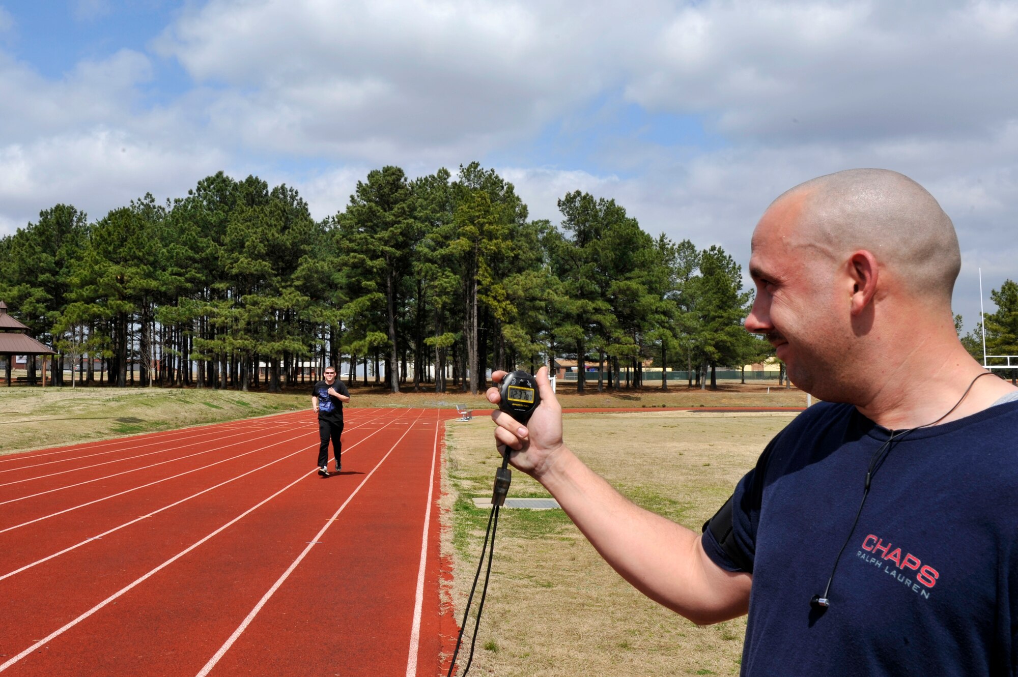 Staff Sgt. Michael Price, 314th Aircraft Maintenance Squadron engine specialist, sprints towards the finish line at the base outdoor track March 17 while Staff Sgt. Adam Vandiver, 314th AMXS crew chief, records Sergeant Price's practice mile and a half run time.  Sergeants Price and Vandiver prepare for their mile and a half run together. (U.S. Air Force photo by Senior Airman Christine Clark)