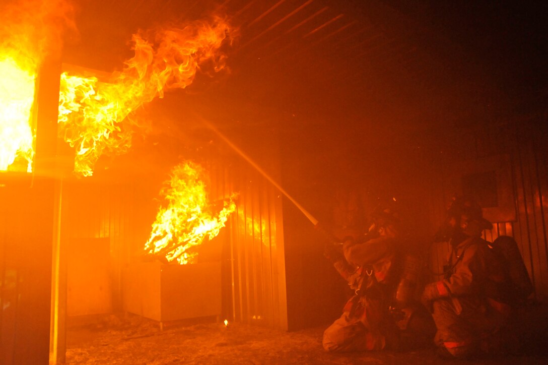 Firefighters from the 316?th Civil Engineer Squadron fight a simulated fire inside a live fire training building March 5, 2010, at Joint Base Andrews Md.  Regular training conducted, inside the building, ensures the firefighters can experience the mental and physical challenges of fighting a fire. The 316?th CES firefighters train to improve teamwork, accountability, attention to detail and the proper donning of personal protective equipment. (U.S. Air Force photo by Airman 1st Class Perry Aston) (Released)
