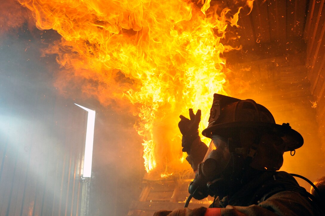 Michael McCartney 316th Civil Engineer Squadron firefighter instructs firefighters to extinguish a simulated fire with water during live fire training in the live fire training building March 5, 2010, at Joint Base Andrews Md.  Regular live fire trainings let the firefighter gain the skills needed to think critically and clearly and solve problems quickly, under extreme stress during a real structure fire. (U.S. Air Force photo by Airman 1st Class Perry Aston) (Released)